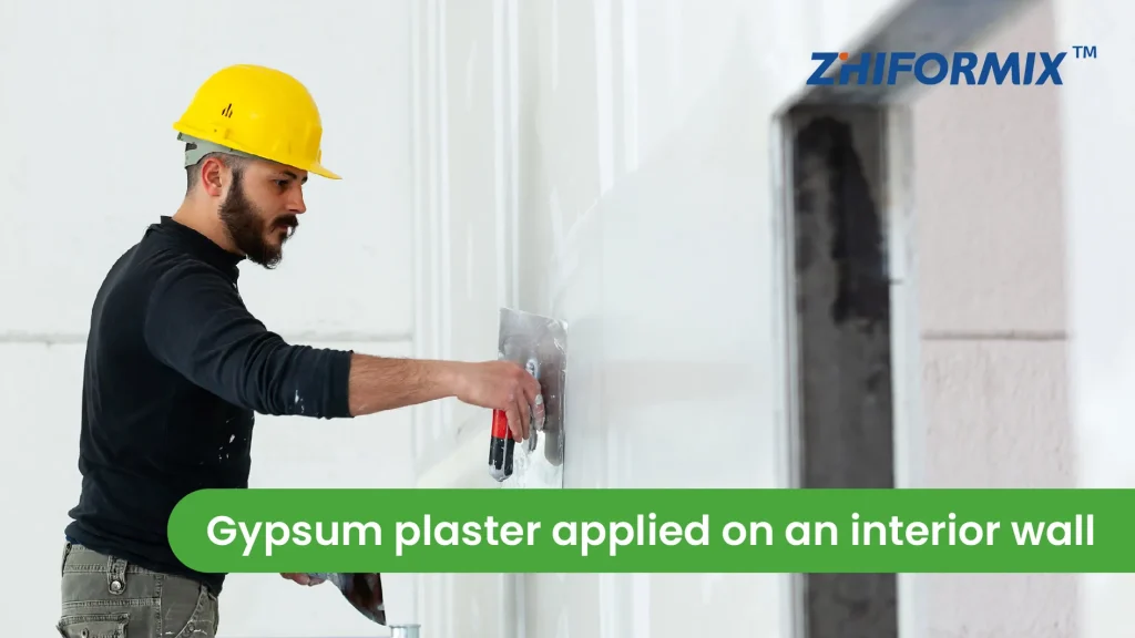 Worker spreading gypsum plaster on an interior wall
